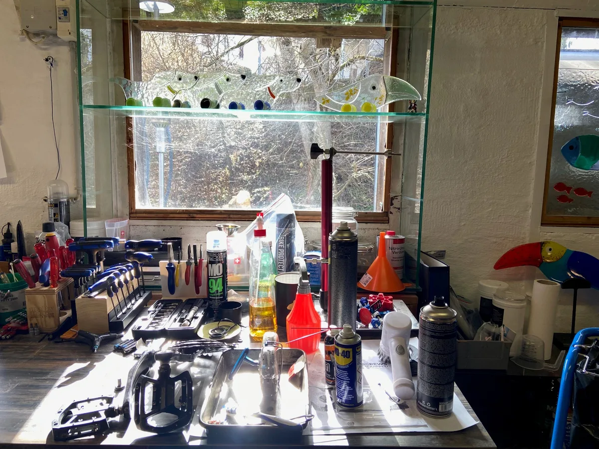 Nur die Glasfiguren erinnern noch an seine Mutter, die hier ein Kunstatelier hatte. Ein Tisch mit klassischem Velowerkzeug. Oben am Fenster: Dackel aus Glas.